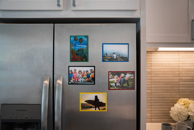 Magnetic photo pocket frames in Green, Blue, Black, Red and Yellow displayed on stainless steel fridge.